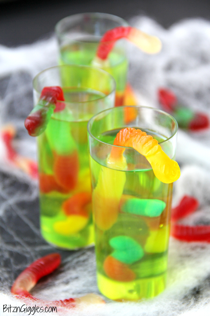 Gummy Worm Jello Shooters - A fun kids treat perfect for mad scientist parties and Halloween! Gummy worms are suspended in green jello and the treat is garnished with a full size worm "crawling" out of the glass!