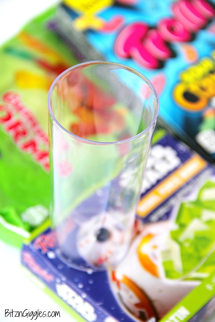 Gummy Worm Jello Shooters - A fun kids treat perfect for mad scientist parties and Halloween! Gummy worms are suspended in green jello and the treat is garnished with a full size worm "crawling" out of the glass!