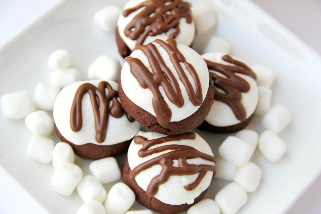 Surprise Inside Marshmallow Brownie Bites - Bite-sized brownie cookies filled with a caramel center and topped with marshmallow and chocolate drizzle!