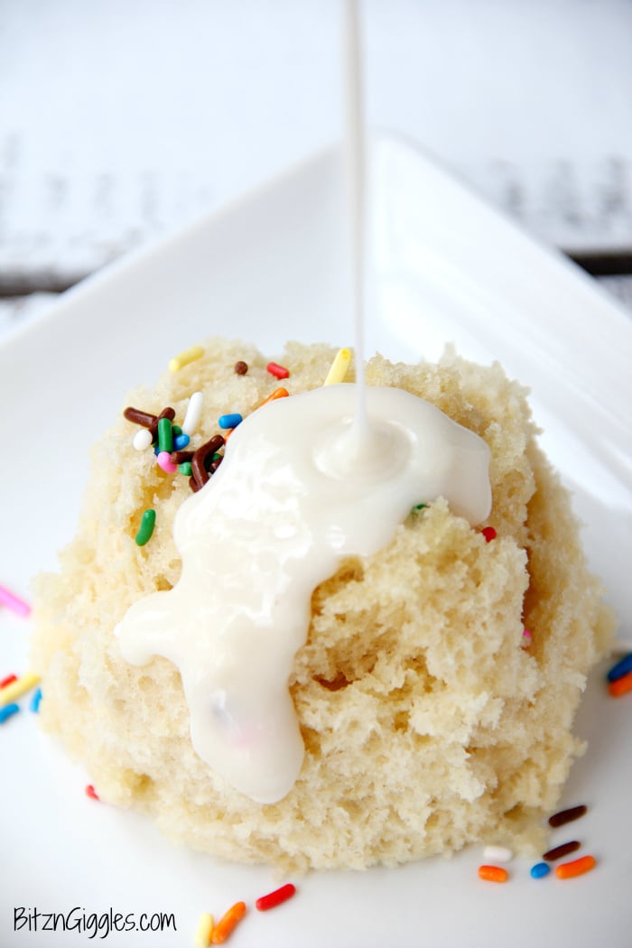 Vanilla Mug Cake - Ready in 90 seconds! This mug cake is moist, delicious and topped with a lovely vanilla icing that soaks into the cake and infuses it with sweetness! #mugcake #vanillacake #recipe #easymugcake #microwavedessert #bitzngiggles