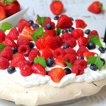 Triple Berry Pavlova - This meringue cake is crisp on the outside and soft and light on the inside! Topped with homemade whipped cream and fresh berries, it's such an elegant, light and delicious dessert!