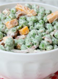 Easy Pea Salad - A summer salad perfect for potlucks and gatherings. Crisp green peas float alongside bacon, cheddar cheese and thinly sliced red onion in a sweet and creamy dressing.