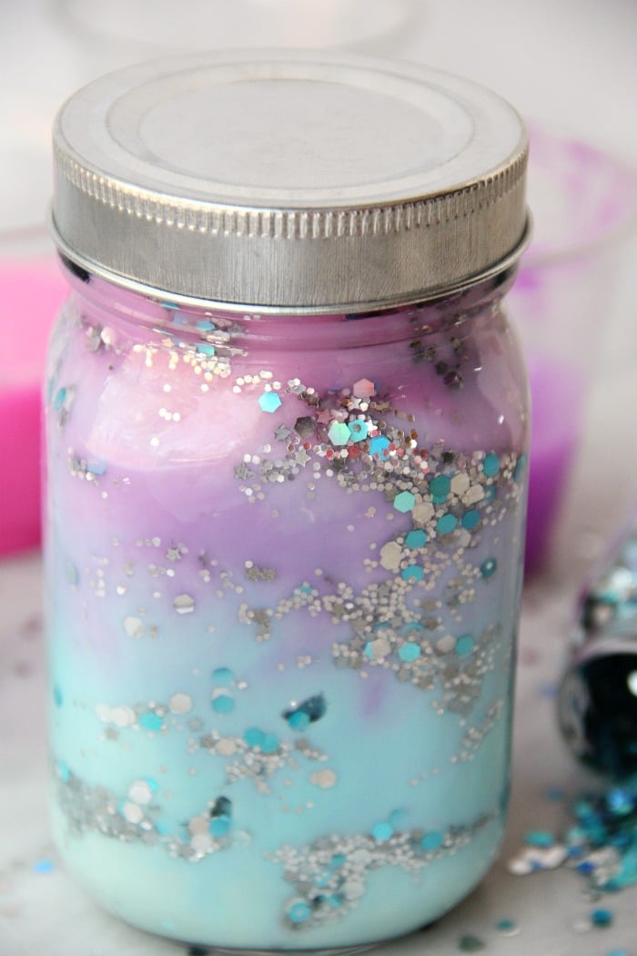 DIY Galaxy Jar -A gorgeous craft for kids, teens or even adults who love color and glitter! Simply layer cotton balls, acrylic paint, water and glitter shapes to create your own galaxy in a jar!