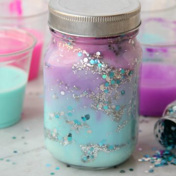 DIY Galaxy Jar -A gorgeous craft for kids, teens or even adults who love color and glitter! Simply layer cotton balls, acrylic paint, water and glitter shapes to create your own galaxy in a jar!