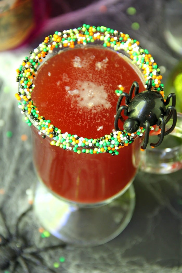 Spooky Halloween Punch - This Halloween punch is only three ingredients! When served in a nonpareil-rimmed glass, the color of the candy starts dripping eerily into the punch, creating fun black streaks and darkening the color of the drink!