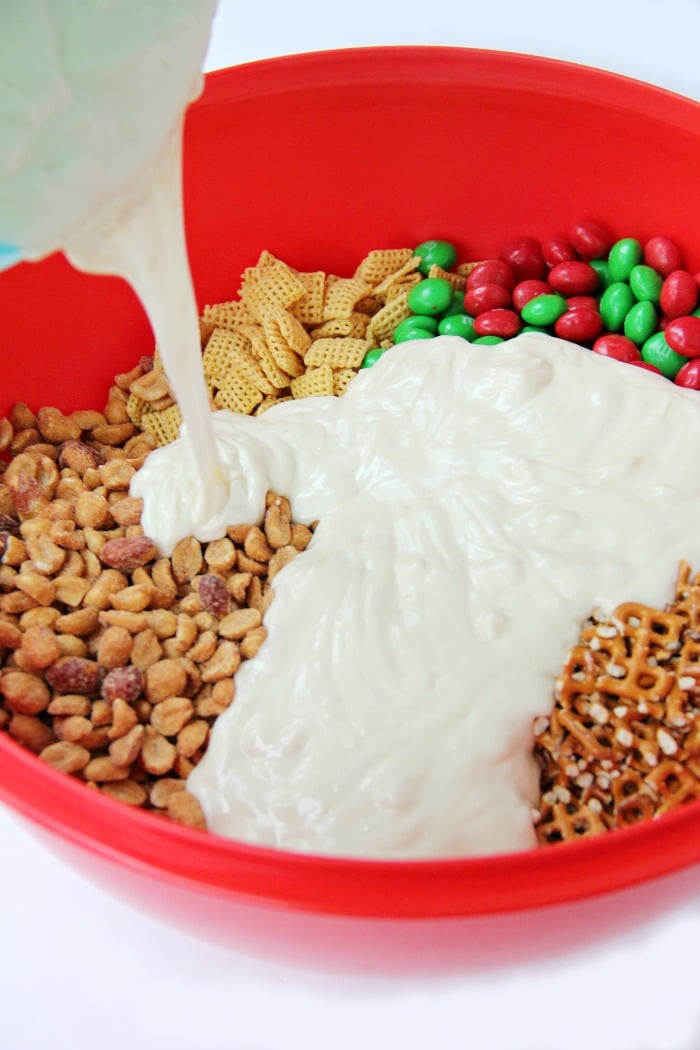 Easy Reindeer Chow - A delicious snack mix filled with pretzels, peanuts, Cheerios, Chex and M&Ms covered in white chocolate. Great for snacking and gift giving!