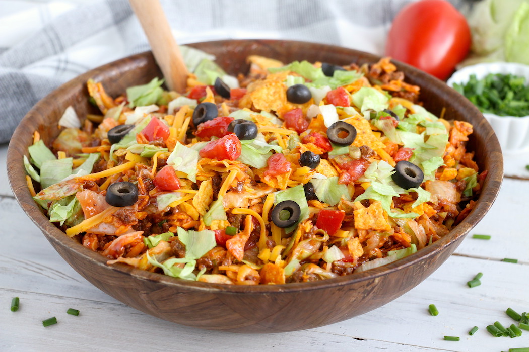 Dorito Taco Salad - This crunchy and zesty salad is made with seasoned ground beef, veggies, cheese and Doritos, then tossed with Catalina dressing. So delicious and serves a crowd! 