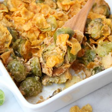 Scooping out brussels sprouts from casserole dish
