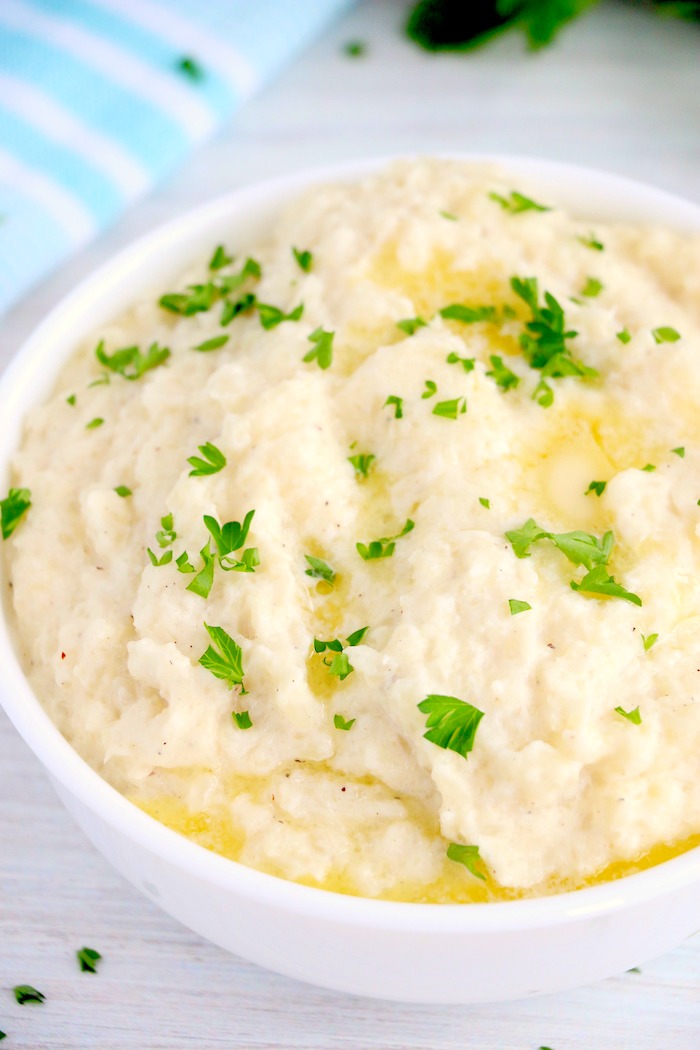 bowl of mashed cauliflower with butter and parsley