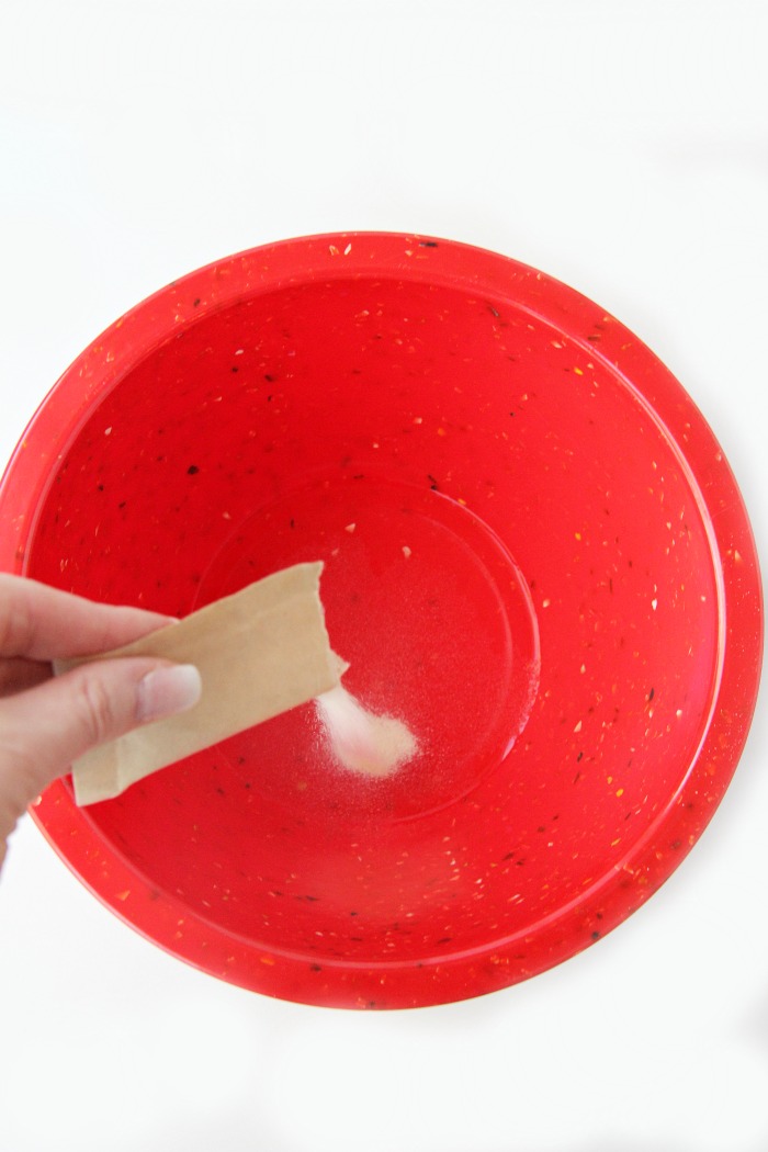 pouring gelatin into water in red mixing bowl