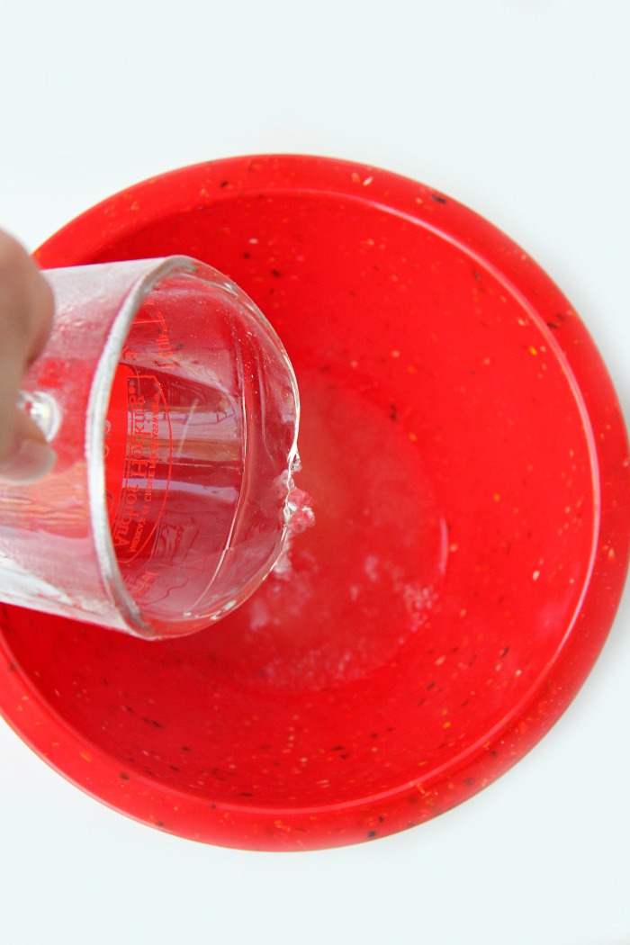 Adding water to a red mixing bowl
