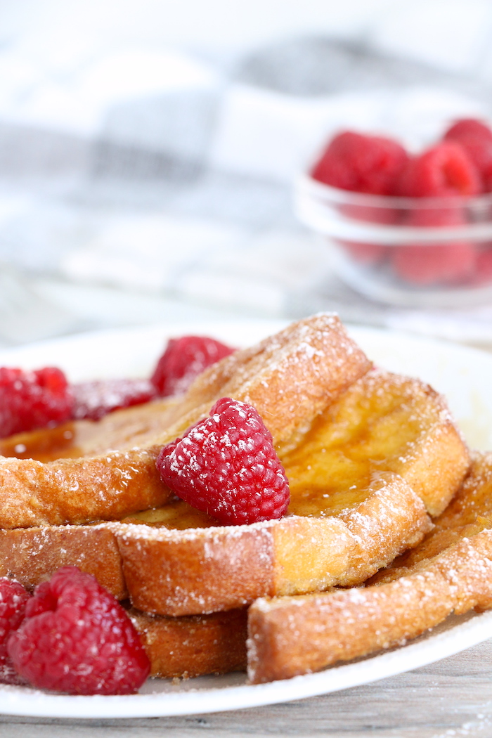 French toast covered with maple syrup, powdered sugar and raspberries