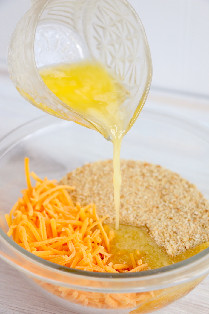pouring butter into bowl of cheese and breadcrumbs