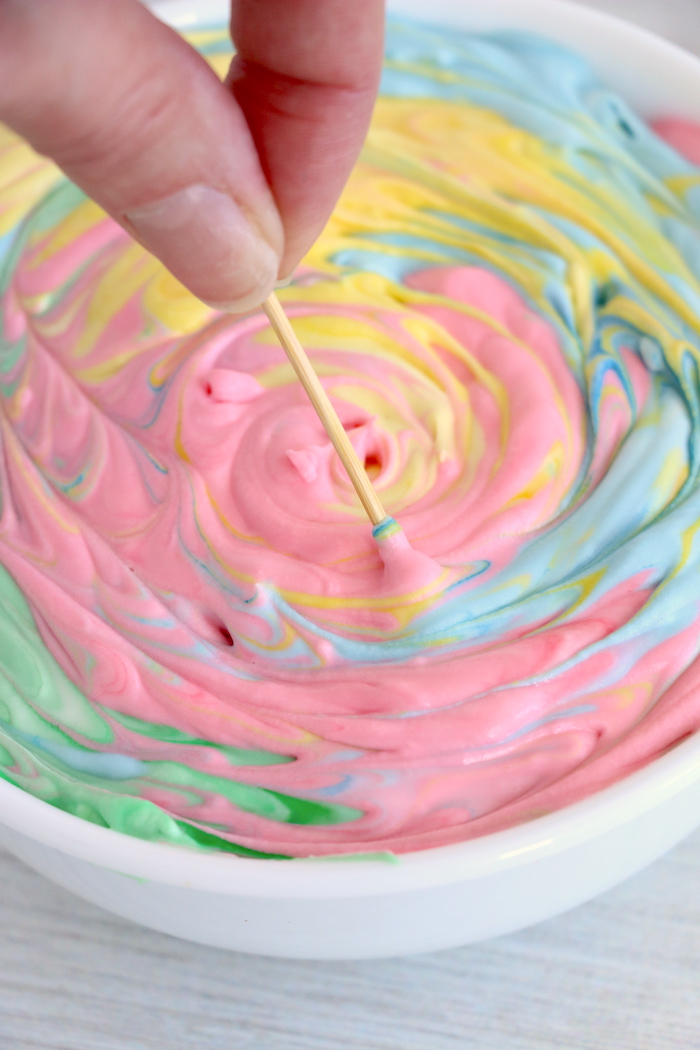 Making rainbow swirls in fruit dip with a toothpick