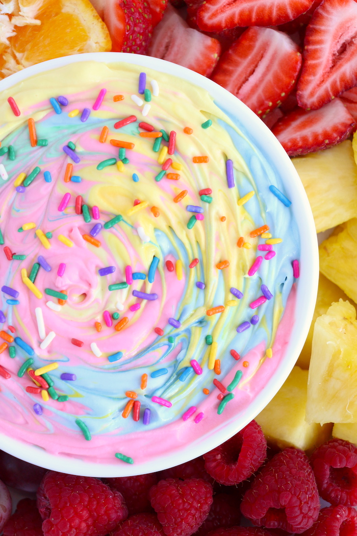 Rainbow fruit dip with sprinkles surrounded by fruit