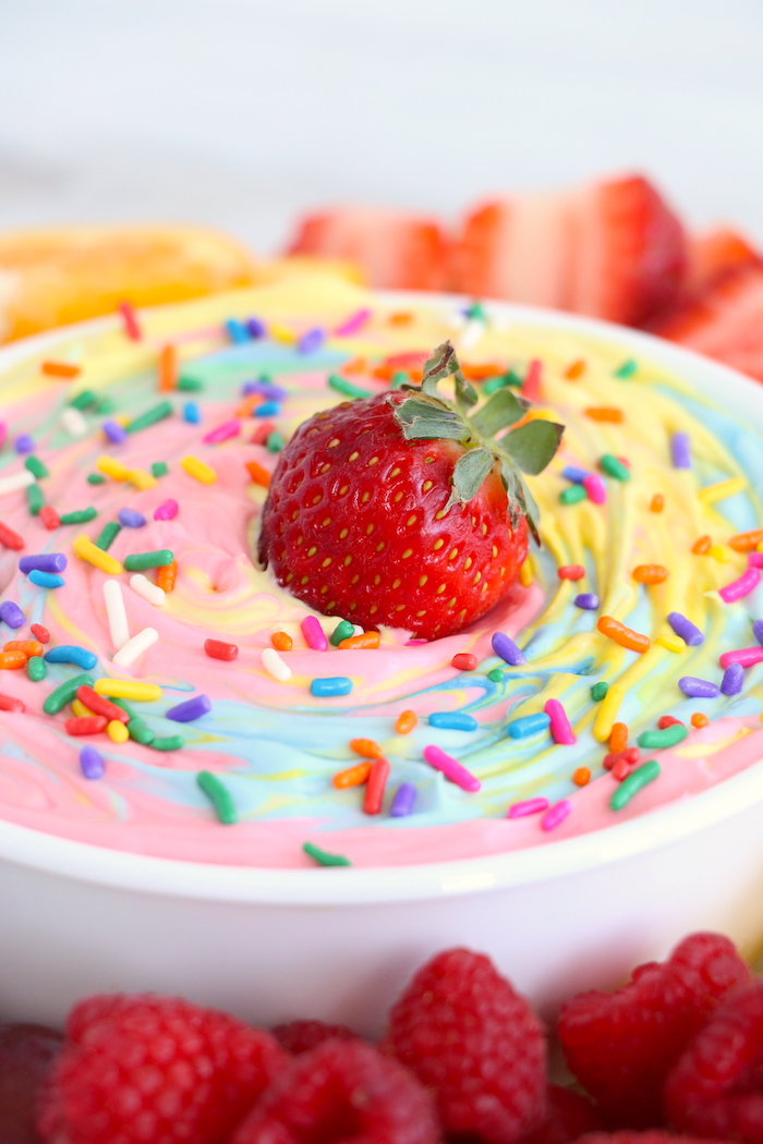 Rainbow fruit dip with sprinkles topped with a strawberry