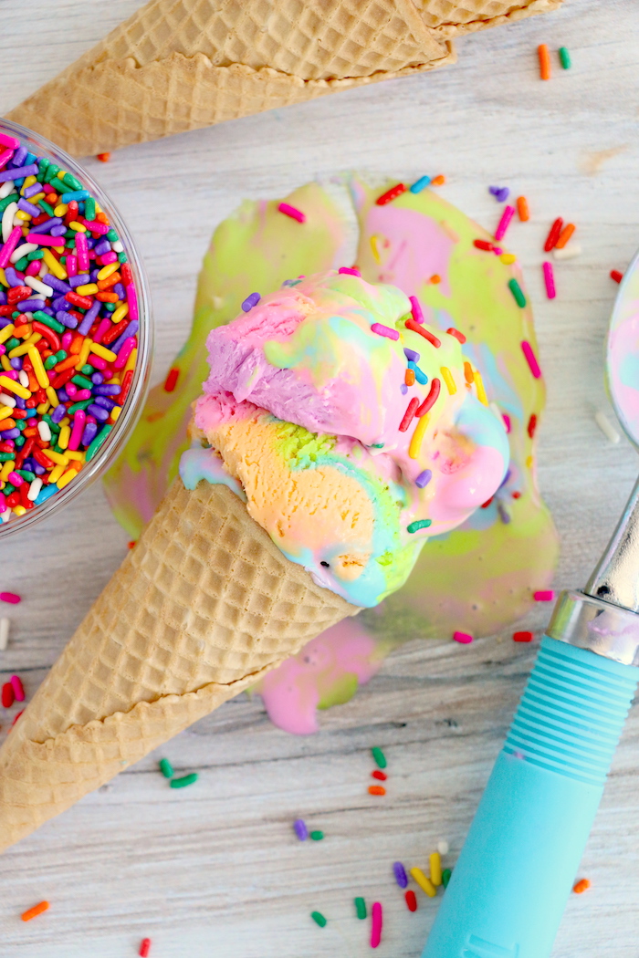 Rainbow ice cream in cone melting on counter