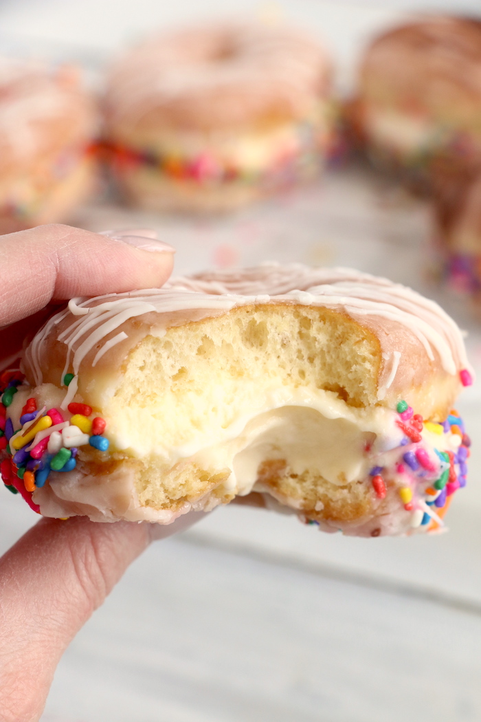 holding a donut ice cream sandwich with a bite out of
