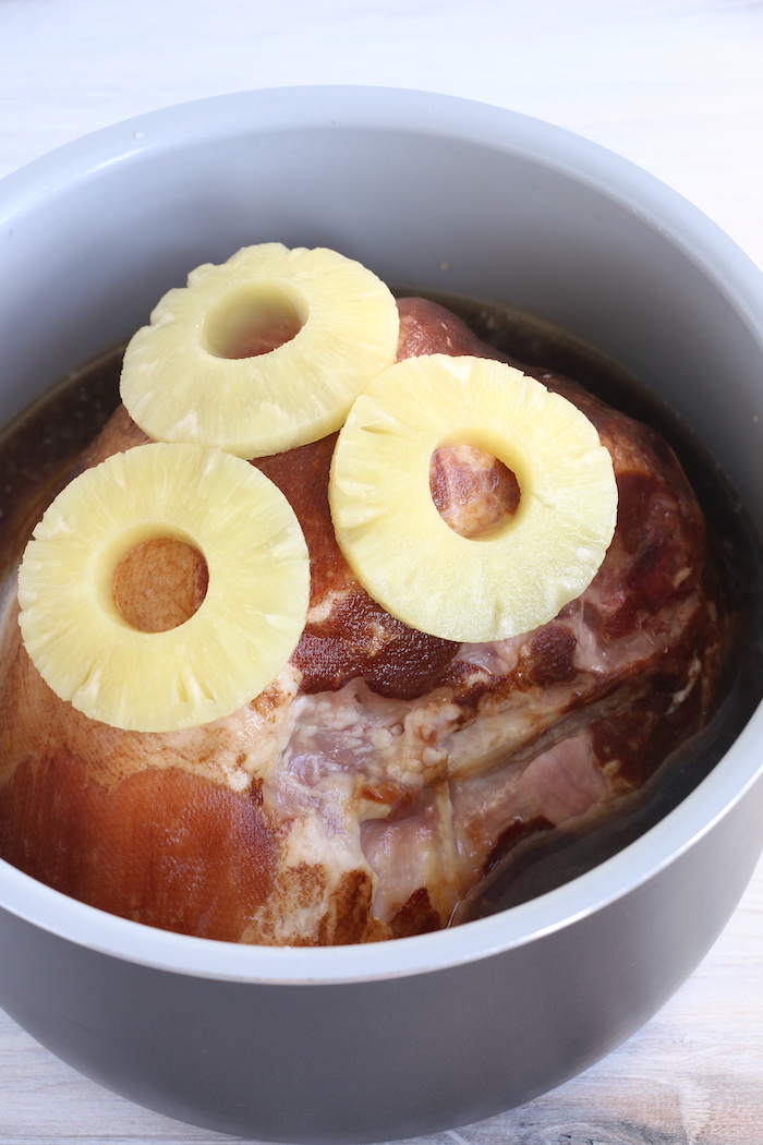 Pineapple slices on top of ham in cooking pot