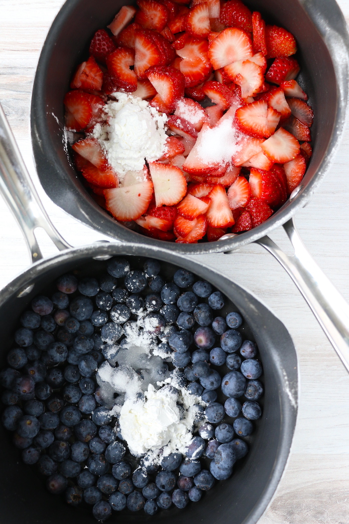 Blueberries and strawberries in sauce pans