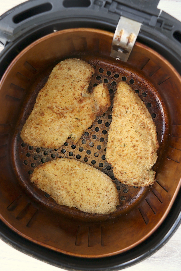 Breaded chicken breasts in air fryer basket