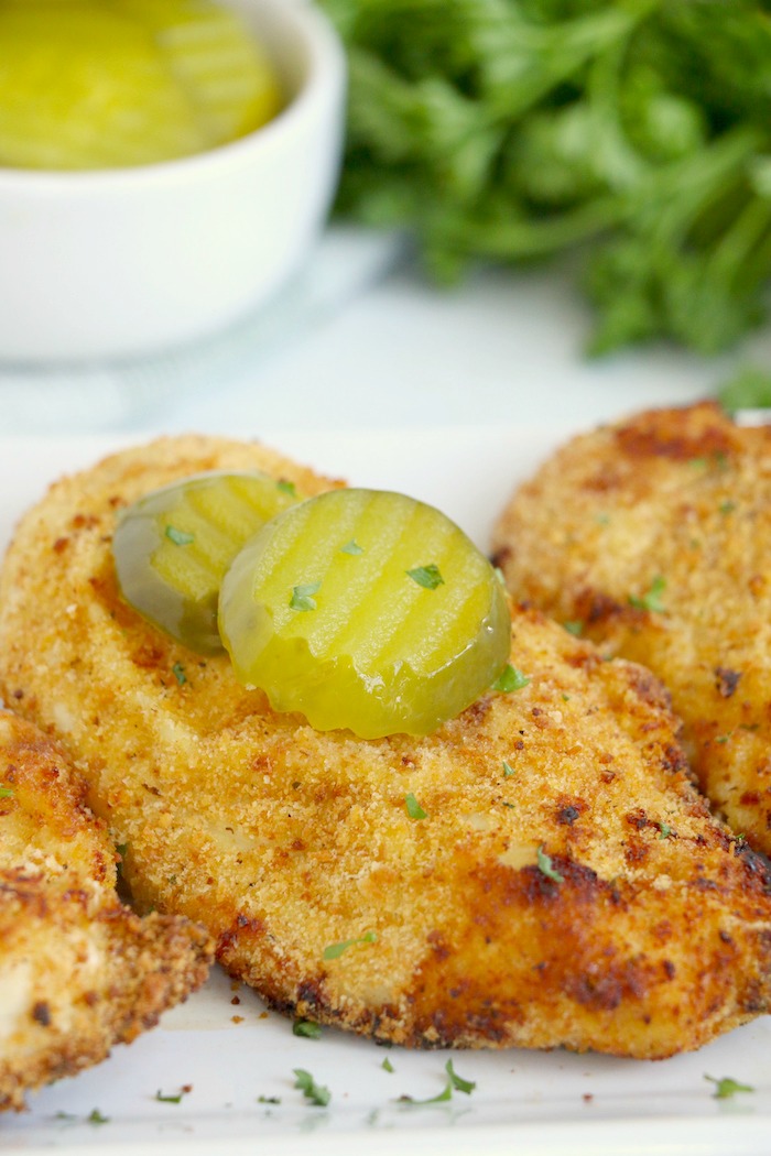 Breaded chicken breasts with dill pickle slices on top