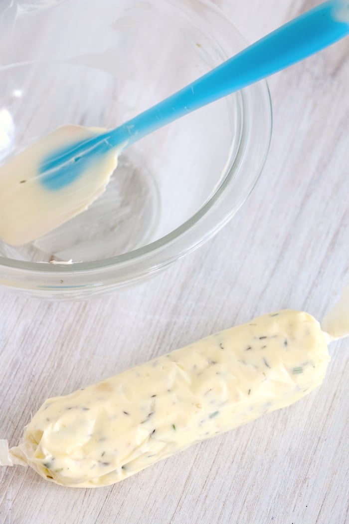 roll of garlic butter next to glass bowl