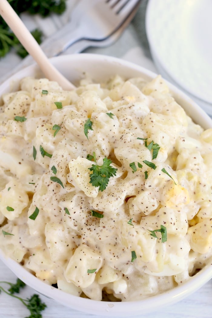 Potato salad in white bowl with spoon