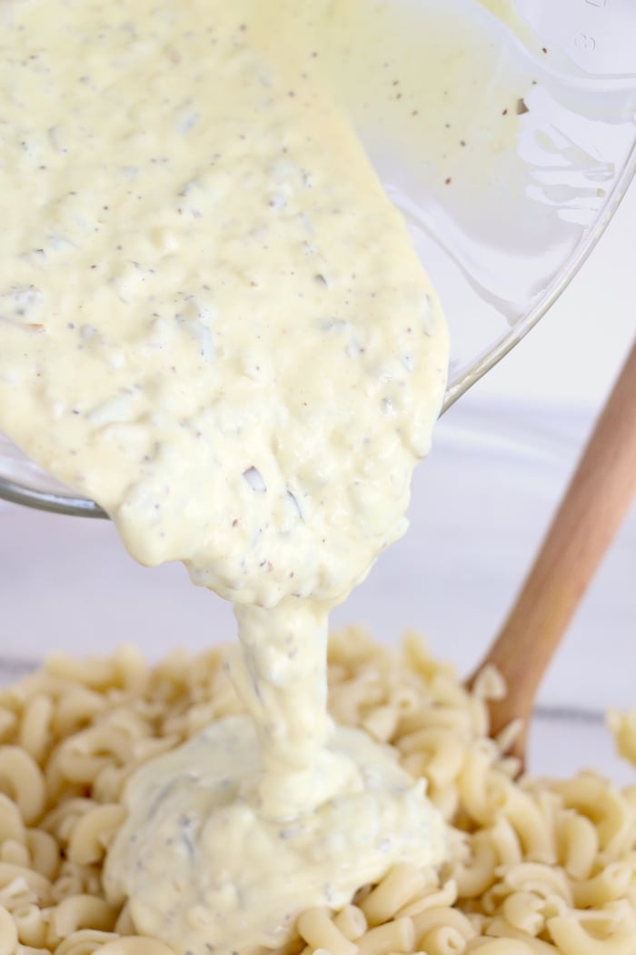 Pouring dressing on tuna pasta salad