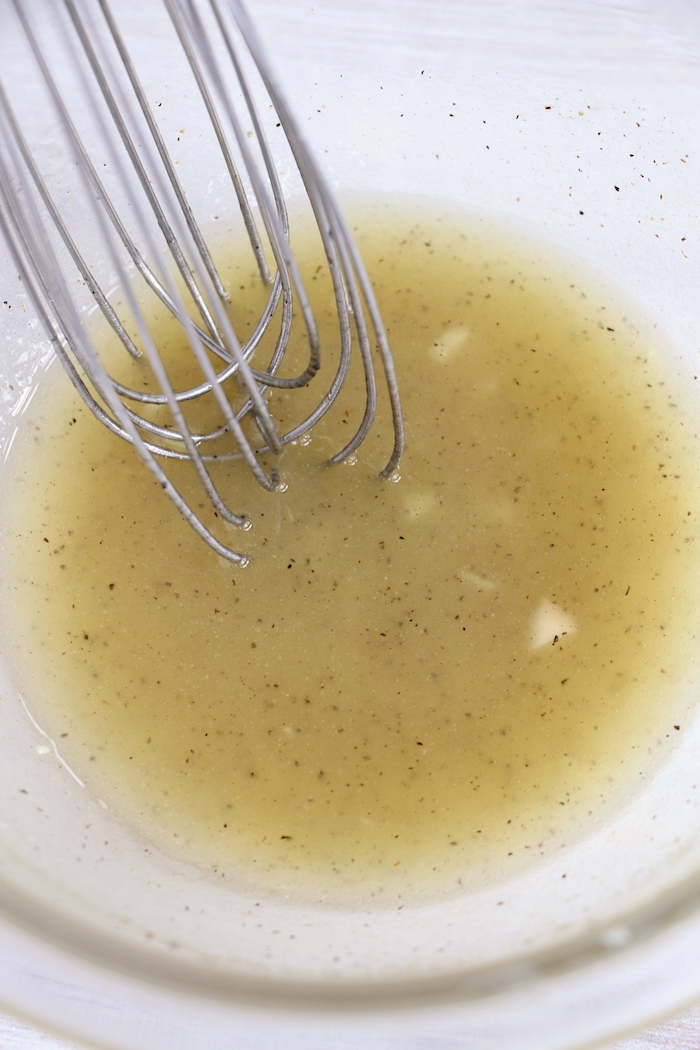 whisking lemon garlic dressing in a bowl