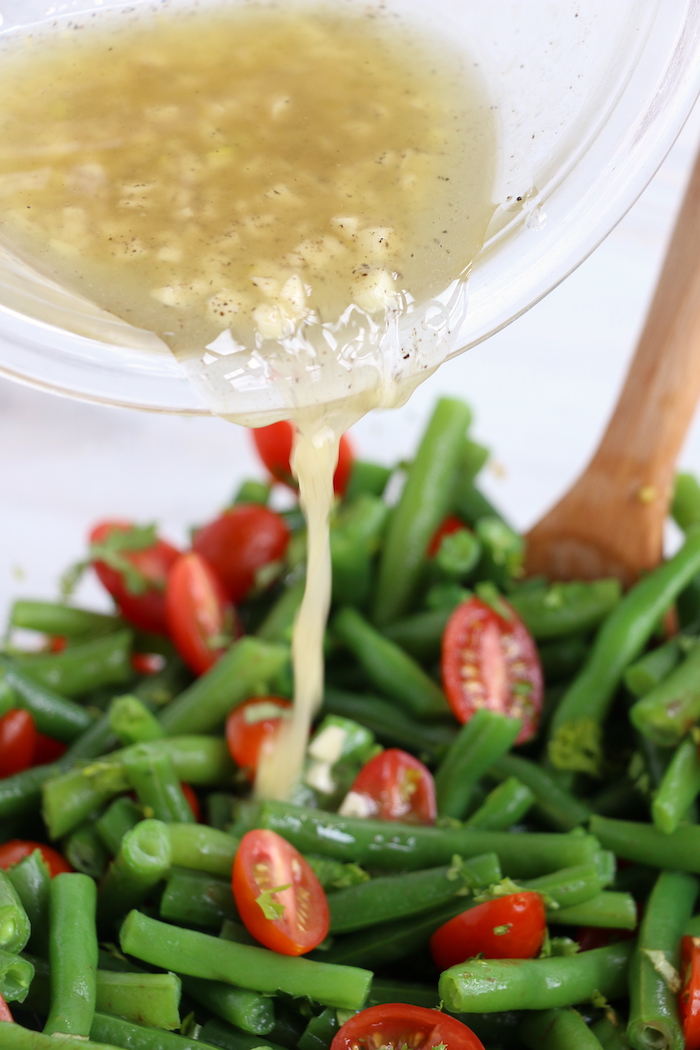 Pouring dressing over green bean salad