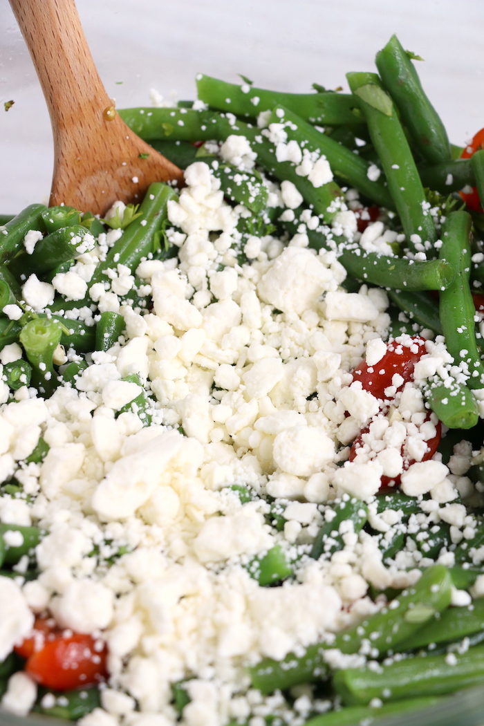 Mixing in feta cheese to green bean salad