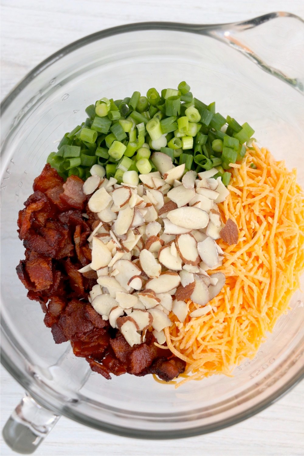 Cheese, almonds, bacon and green onions in a glass bowl