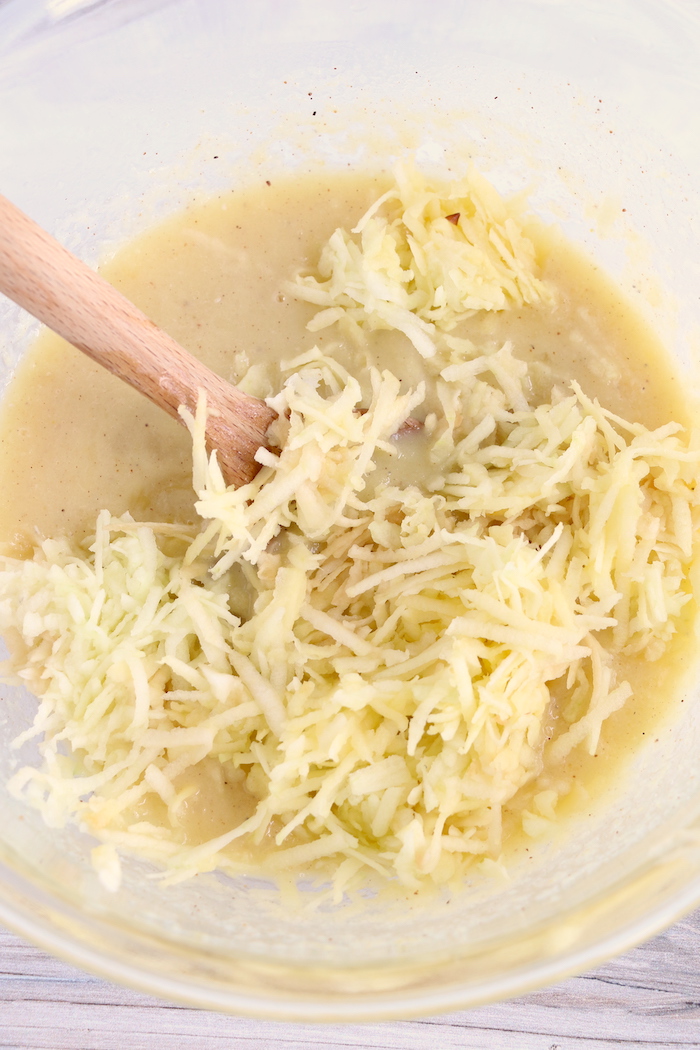 Mixing shredded apples with a wooden spoon