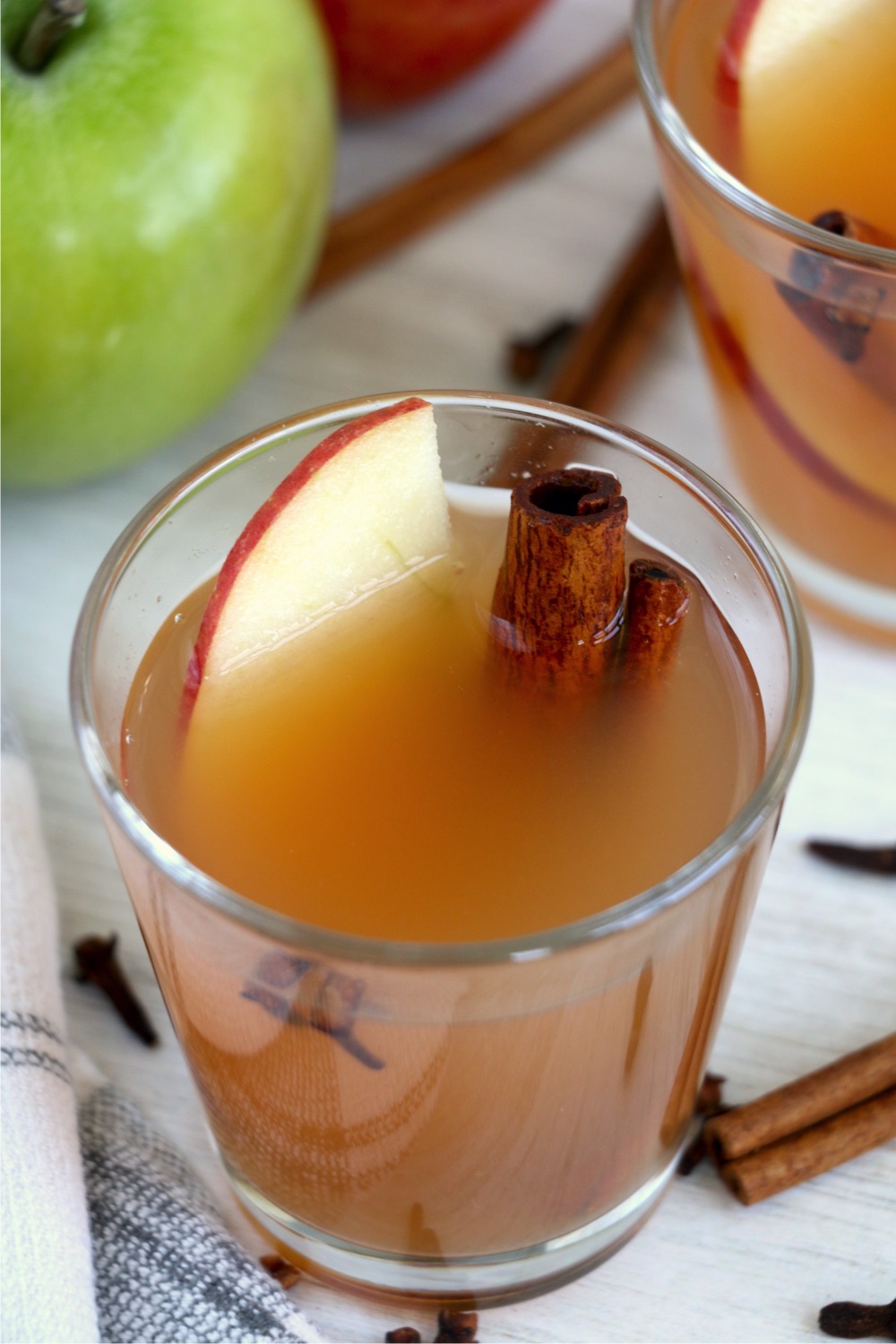 Glass of apple cider with sliced apple and cinnamon sticks