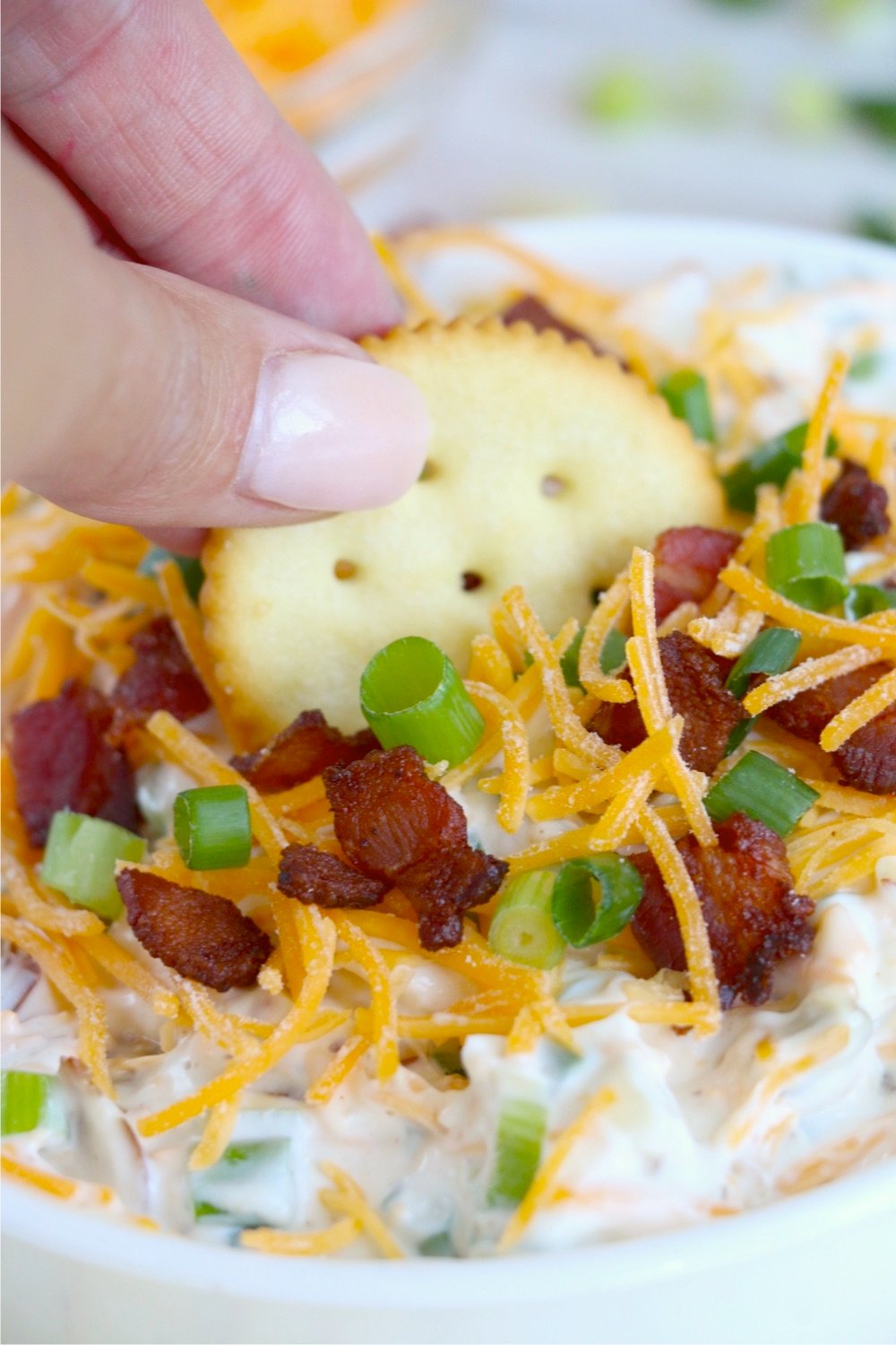 close up of dipping a cracker into Neiman Marcus dip