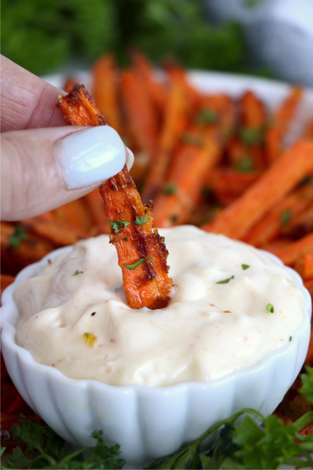 dipping an air fryer carrot fry in spicy mayo sauce