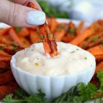 dipping an air fried carrot into spicy mayo sauce