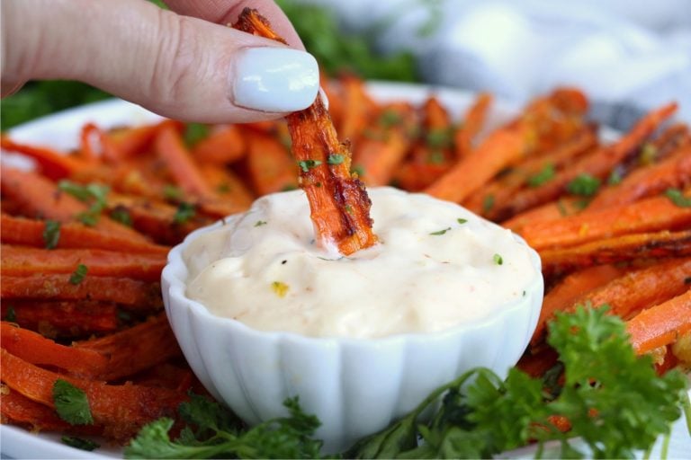 dipping an air fried carrot into spicy mayo sauce