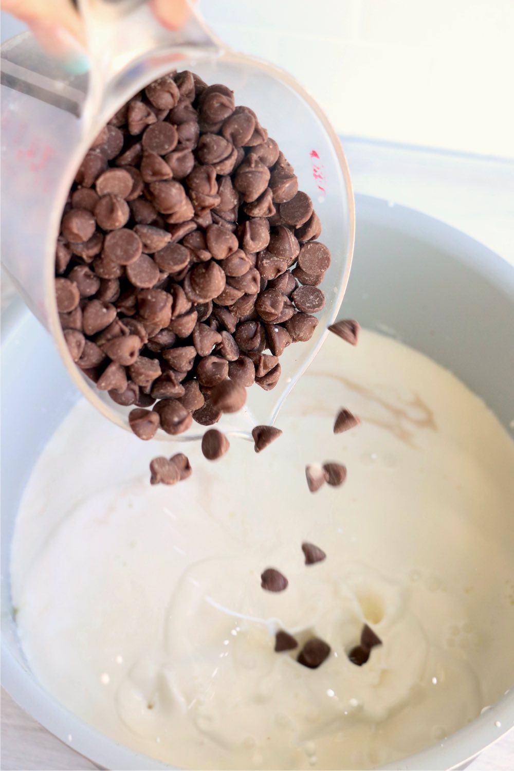 pouring chocolate chips into a Ninja Foodi cooking pot