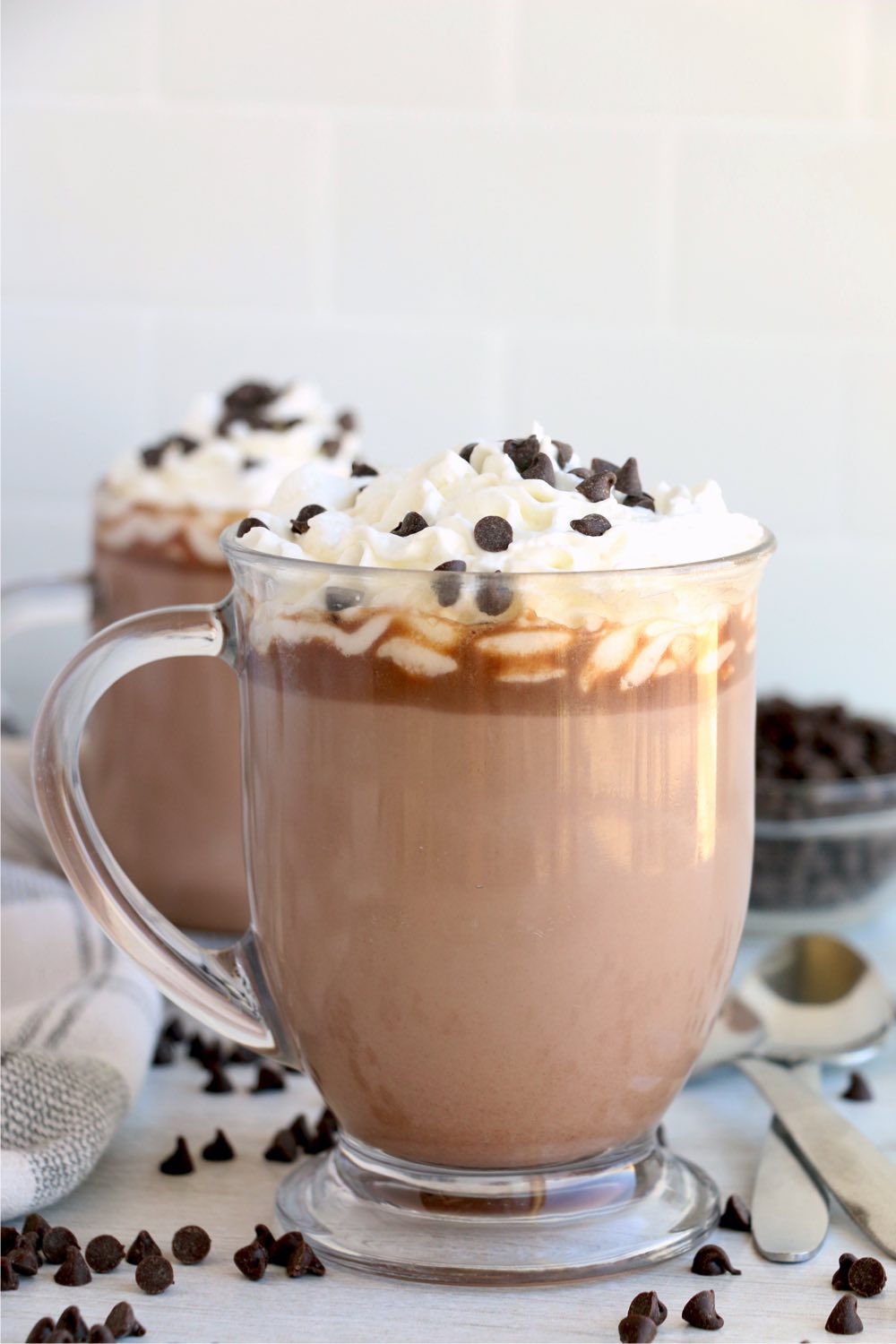 glass mug of hot chocolate with cream and chocolate chips