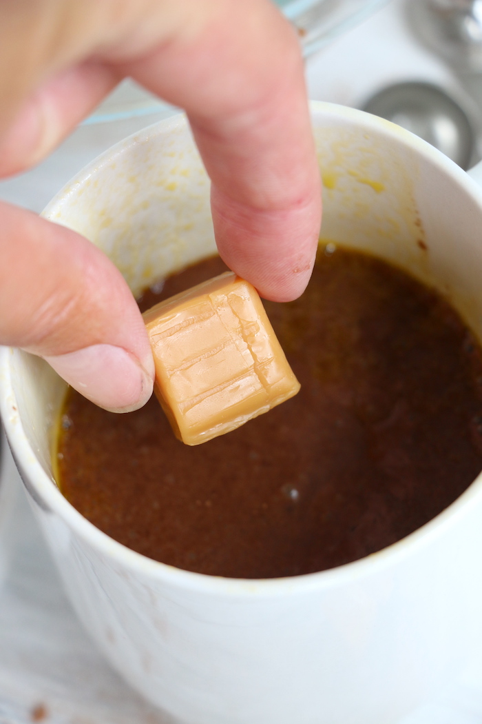 Placing a piece of caramel candy in a chocolate mug cake