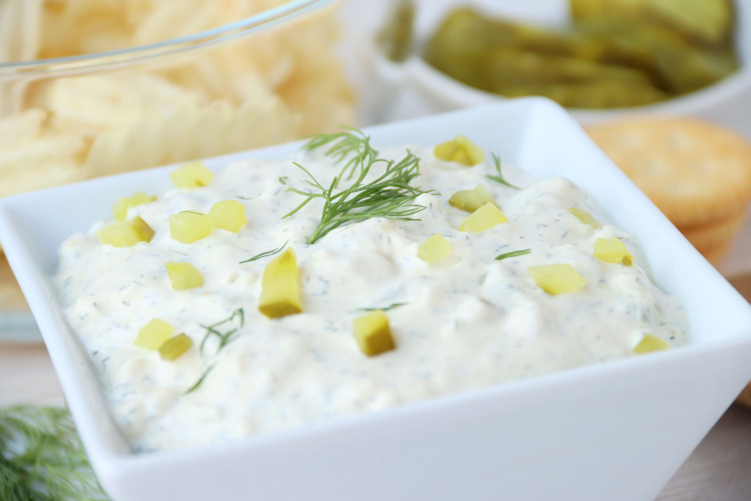 Bowl of dip with pieces of pickle and fresh dill