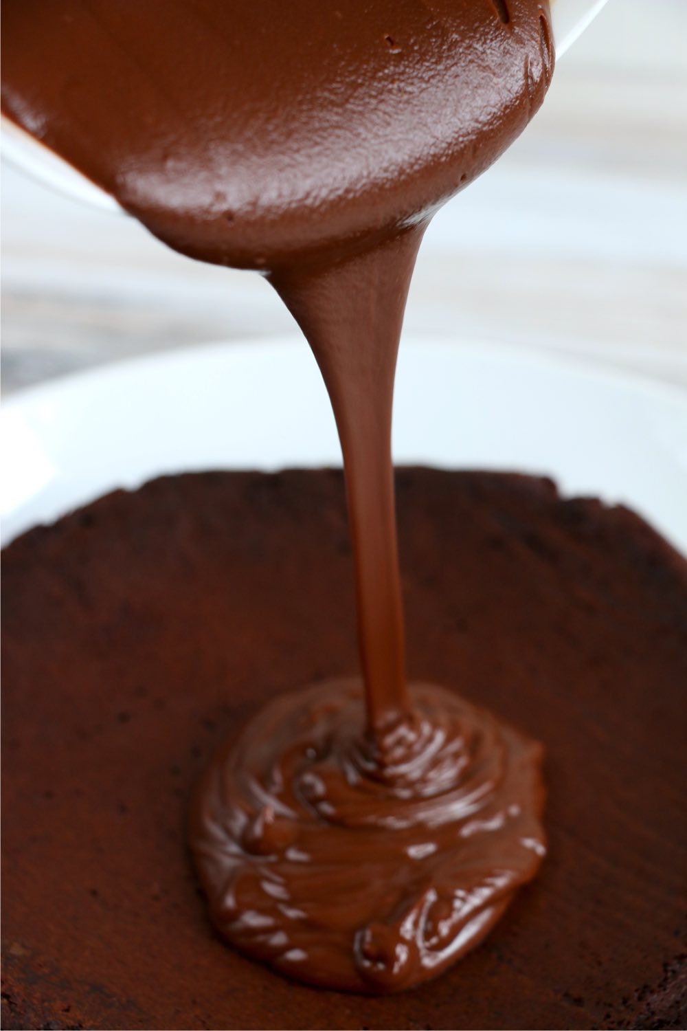pouring ganache over chocolate cake