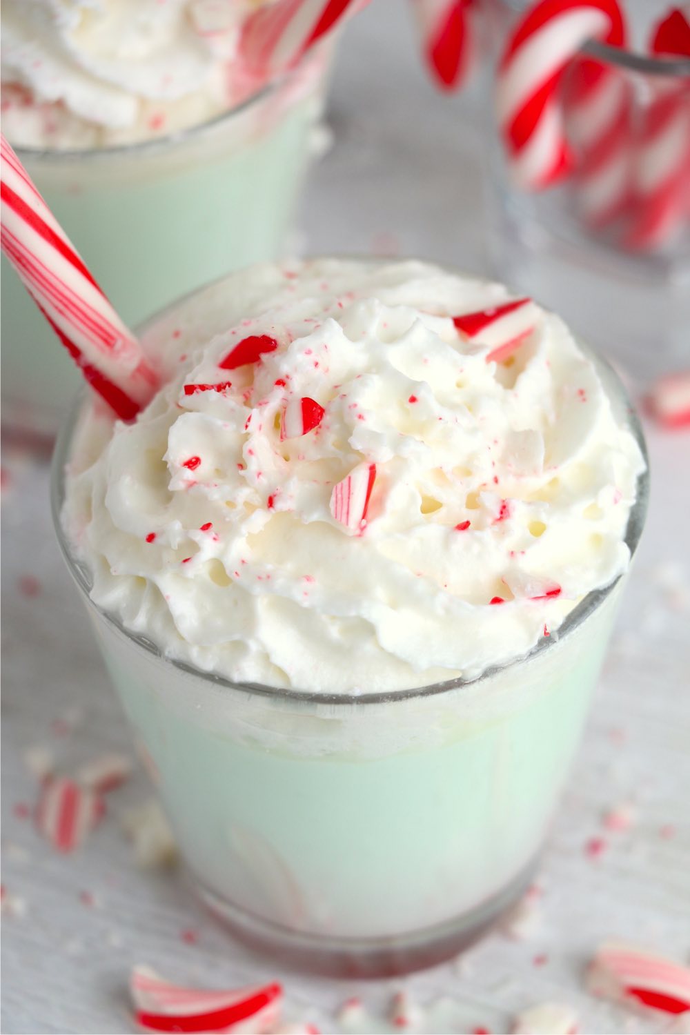 top shot of green hot chocolate topped with whipped cream and peppermint candies