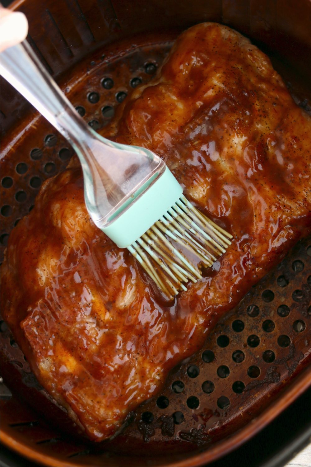 brushing BBQ sauce on ribs in air fryer