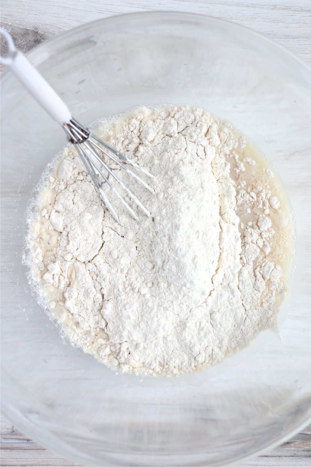 adding flour to bowl of yeast and water
