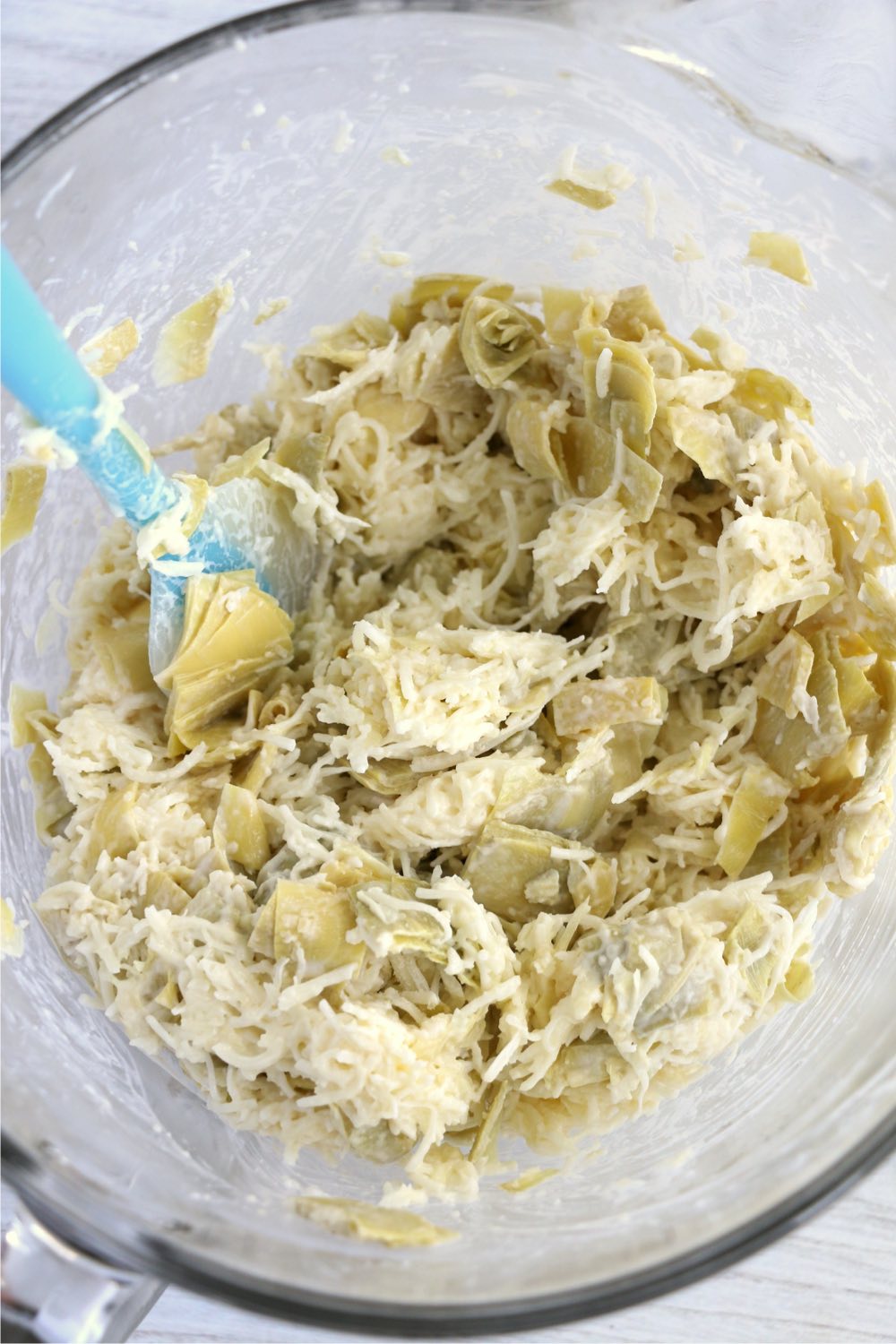 Mixing artichoke hearts with mayonnaise and cheese