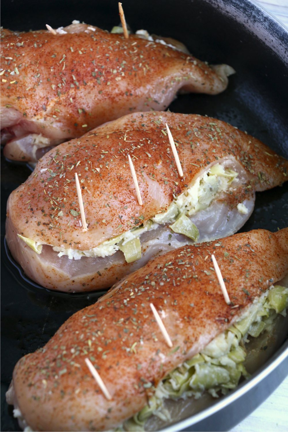 Artichoke stuffed chicken breasts in skillet