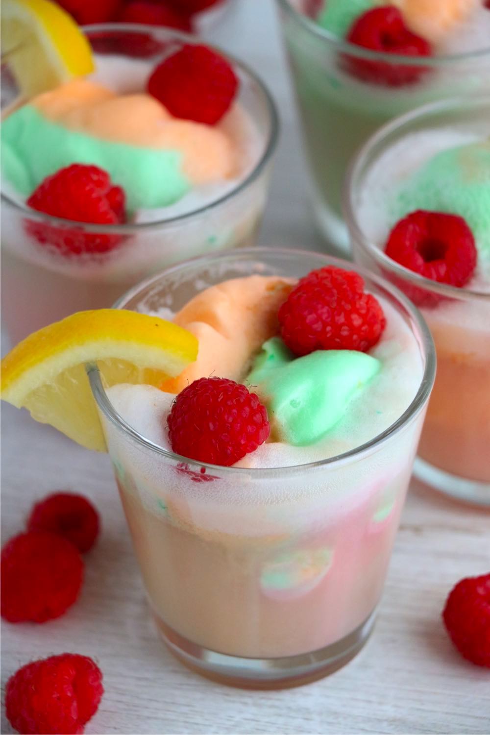 Glass of sherbet punch garnished with raspberries and lemon slices